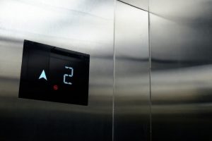 Digital hissdisplay visar våning 2 och pil uppåt mot blanka metalldörrar.