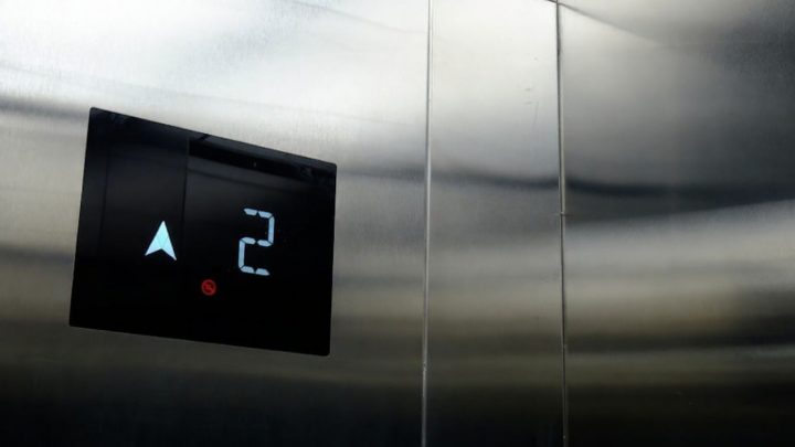 Digital hissdisplay visar våning 2 och pil uppåt mot blanka metalldörrar.