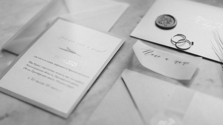 Svartvitt foto av bröllopsinbjudan, vigselringar och sigill.